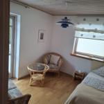 Ein Schlafzimmer mit Bett, Sessel, Tisch und Decke.