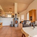 Wohnzimmer mit Kamin, Sofa, TV und Küche im Hintergrund.