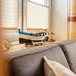 Ein grauer Sofa mit Kissen. Auf dem Fensterbrett steht ein kleines Boot und eine Figur.