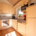 Küche mit Holzschränken, Edelstahlgeräten und Fenster.