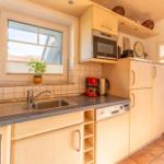 Küche mit Holzschränken, Spüle und Fenster. Mikrowelle und Kaffeemaschine vorhanden.