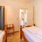 Zwei Betten mit weißen Bettwäsche, Kinderhochstuhl und Kleiderschrank mit Vorhang.