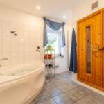 Badezimmer mit Whirlpool, Sauna und Fenster mit blauen Vorhängen.