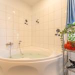 Dusche mit Badewanne, Wandfliesen mit Fischmotiven und Handtuchhalter mit Handtuch.