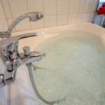 Eine Whirlpool-Badewanne mit Duschkopf und Chromarmaturen in einem hellen Badezimmer.