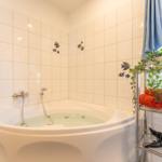 Bad mit Eckbadewanne, Fischfliesen, Handtuchständer und Fenster.