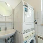 Waschmaschine und Trockner stehen in einem Raum mit Waschbecken und Spiegel.