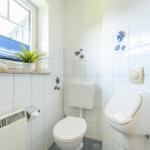 Badezimmer mit Toilette, WC und Fenster mit Pflanze und Ente.