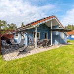 Blauer Ferienhaus mit Terrasse, Liege und Sitzgruppe im Garten.