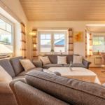 Wohn- und Essbereich mit Sofa, Tisch und Fenstern.