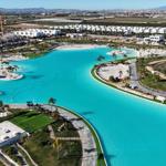 Large pool with beach area and surrounding green spaces