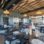 Modern dining room with tables, chairs, and ceiling lights.