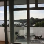 Blick auf Wasser und Grün von der Terrasse mit Tisch und Stühlen.