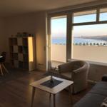 Wohnung mit Blick auf Wasser und Stadt. Sitzgelegenheiten, Tisch, Schrank und Terrasse.