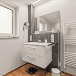 Badezimmer mit Waschbecken, Spiegel, Heizung und Fenster.