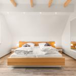Schlafzimmer mit Holzbett, Fenster und Spiegeltür