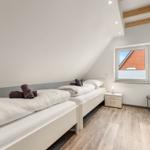 Zimmer mit zwei Betten, Schrank und Fenster mit Blick auf Dach