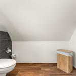 Badezimmer mit Toilette, Heizung und Bambus-Korb.