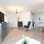 Wohnung mit Küche, Essbereich und Fernseher. Holzboden und moderne Möbel.