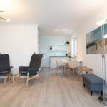 Wohn- und Essbereich mit Küchenzeile, zwei Sesseln und Bodenheizung.