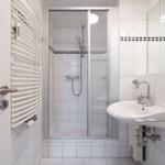 Badezimmer mit Dusche, Waschbecken und Heizkörper