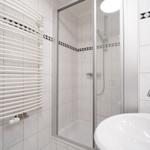 Badezimmer mit Dusche, Waschbecken und Heizkörper