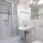 Badezimmer mit Dusche, Waschbecken und Heizkörper