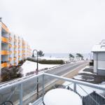 Blick vom Balkon auf schneebedeckte Straße, Strand und Gebäude.