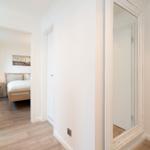 Flur mit Spiegel und Blick in Schlafzimmer mit Bett und Nachttisch.