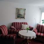 Wohnzimmer mit gestreiftem Sofa und zwei Sesseln um runden Tisch.