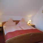 Schlafzimmer mit Doppelbett, zwei Nachttischen und Lampen an der schrägen Wand.