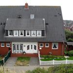 Rotes Haus mit grauem Dach, weißen Fenstern und Vorgarten mit weißem Zaun.