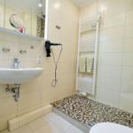 Badezimmer mit Waschbecken, Spiegel, Haartrockner und Dusche mit Mosaikboden.