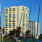 Hochhaus am Hafen mit Segelyachten und klarem Himmel.