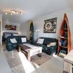 Wohnzimmer mit zwei Sofas, Tisch und Wanddekoration. Küche im Hintergrund sichtbar.