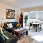 Wohn- und Essbereich mit Sofa, Tisch und Fenstern.