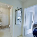 Flur mit Bad und Schlafzimmer. Spiegel, Badewanne, Dusche und Bett sichtbar.