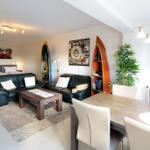 Wohn- und Essbereich mit Sofa, Tisch und Küchenbereich im Hintergrund.