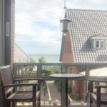 Balkon mit Tisch und Stühlen, Blick auf Meer und Dächer.