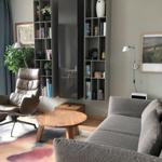 Wohnzimmer mit Sofa, Sessel, Couchtisch und Bücherregal. Durchgang zur Terrasse.