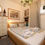 Schlafzimmer mit Doppelbett, Schrank, Wandbild und Vorhängen.