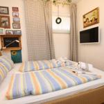 Ein Schlafzimmer mit einem Bett, Vorhängen, Wandbildern und einer Wandhalterung für einen Fernseher.