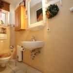 Badezimmer mit Waschbecken, Spiegel, Toilette und Holzschrank.