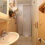 Bad mit Waschbecken, Spiegel, Dusche und Handtuchhalter.