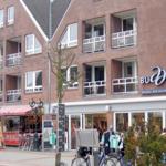 Fassade eines mehrstöckigen Gebäudes mit Balkonen und Geschäften im Erdgeschoss.