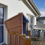 Terrasse mit Wickerliege, Tisch und Stühlen. Blick auf benachbarte Gebäude.