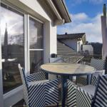 Terrasse mit runden Tisch und vier Stühlen mit schwarz-weißem Muster.