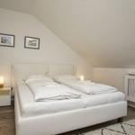 Schlafzimmer mit Doppelbett, Schrank, Nachttisch und Dachfenster.