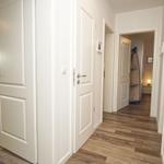 Flur mit weißen Türen und Holzboden. Im Hintergrund ist ein weiterer Raum sichtbar.