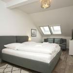 Schlafzimmer mit Doppelbett, Sitzgelegenheit und Dachfenstern.